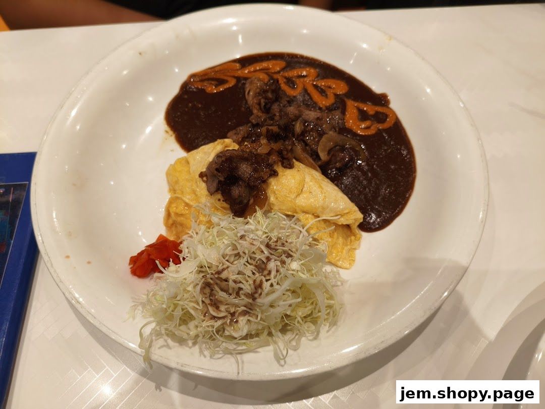 A plate of omurice with beef and sauce, served with shredded cabbage and a side of pickled ginger.