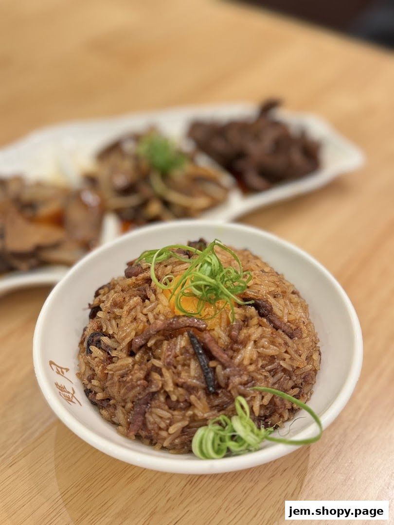 A close-up of a bowl of savory rice with meat and a raw egg yolk.