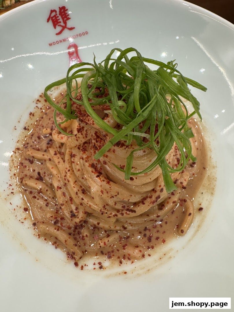 A close-up of a pasta dish with creamy sauce, chili flakes, and green onions.