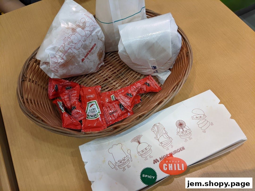 A basket of MOS Burger items including burgers, ketchup packets, and a chili dog box.