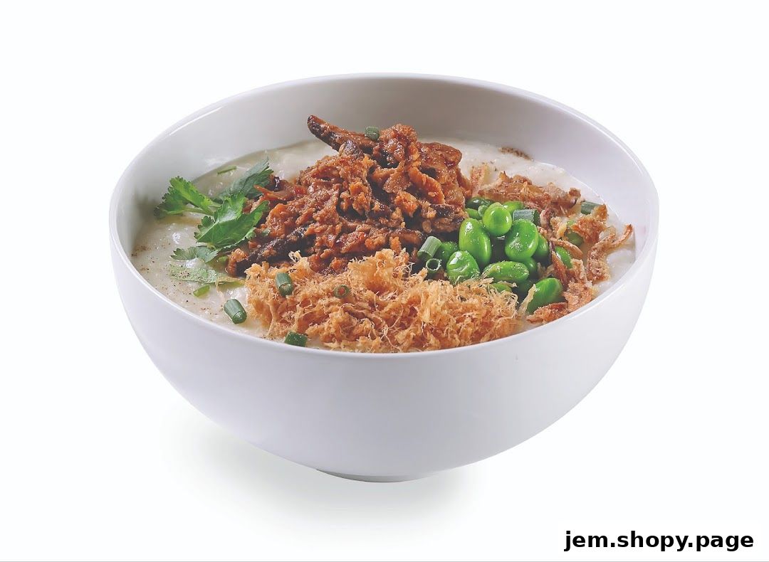 A bowl of congee topped with shredded meat, edamame, and crispy fried shallots.