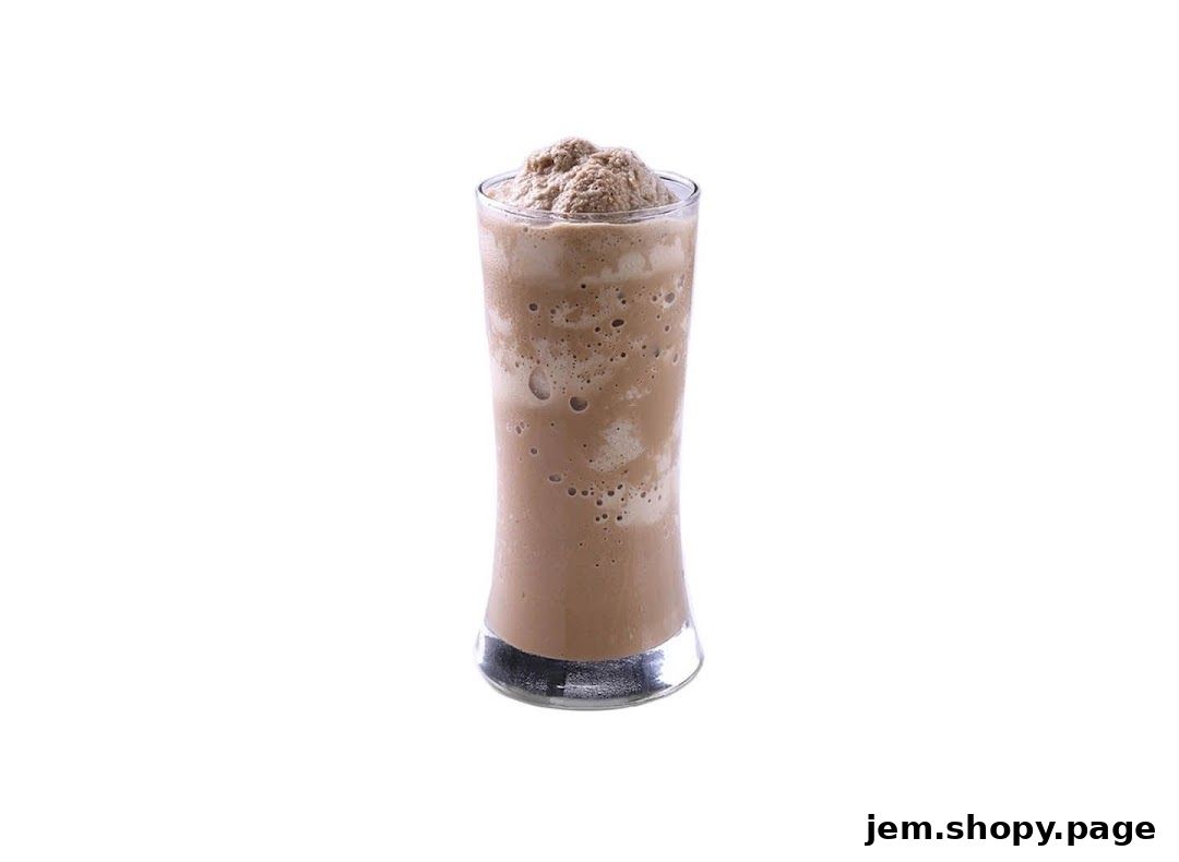 A tall glass filled with a frothy, brown beverage, likely a milkshake or frappe.