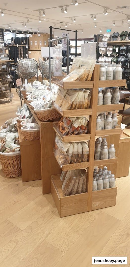 Interior view of MUJI JEM shop showcasing various products on wooden shelves and baskets.