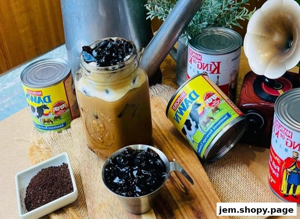 A refreshing iced coffee with grass jelly, surrounded by condensed milk cans and coffee grounds.