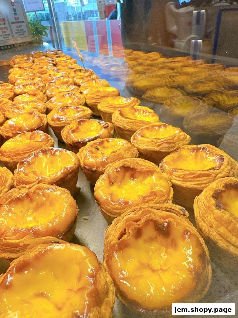 A display of freshly baked Portuguese egg tarts in a bakery.