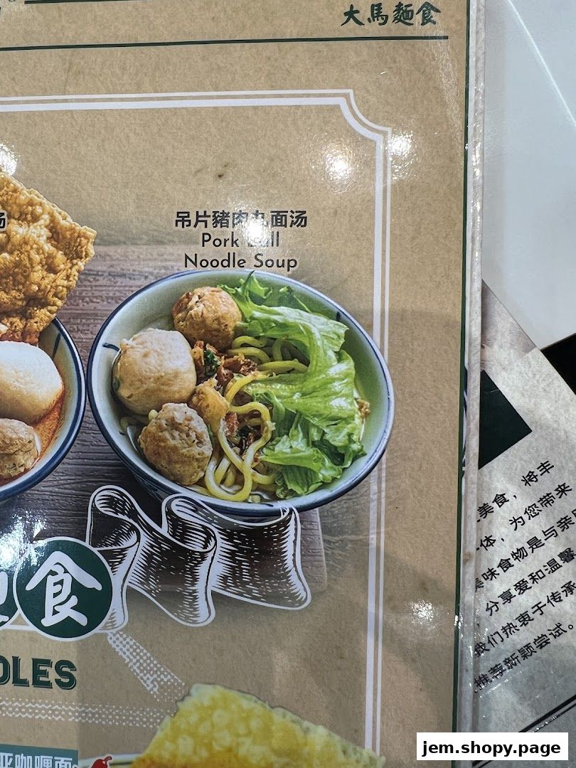 A close-up of a menu item featuring pork ball noodle soup with fresh lettuce.