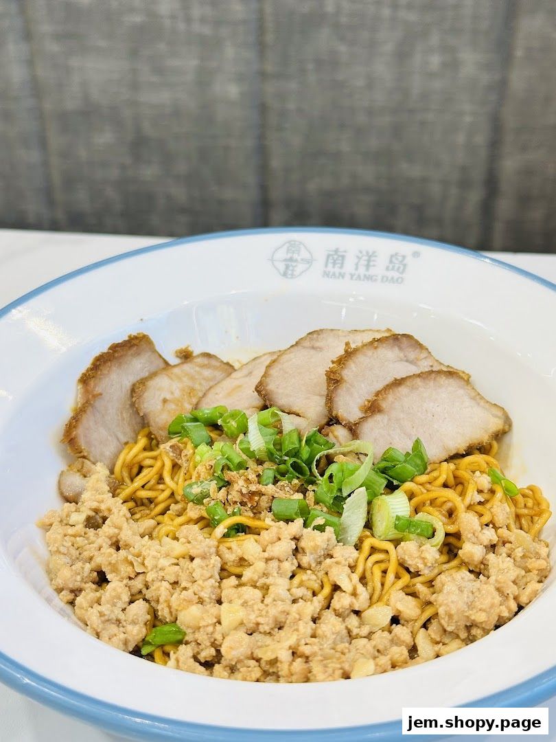 A bowl of noodles topped with sliced meat, minced meat, and green onions.