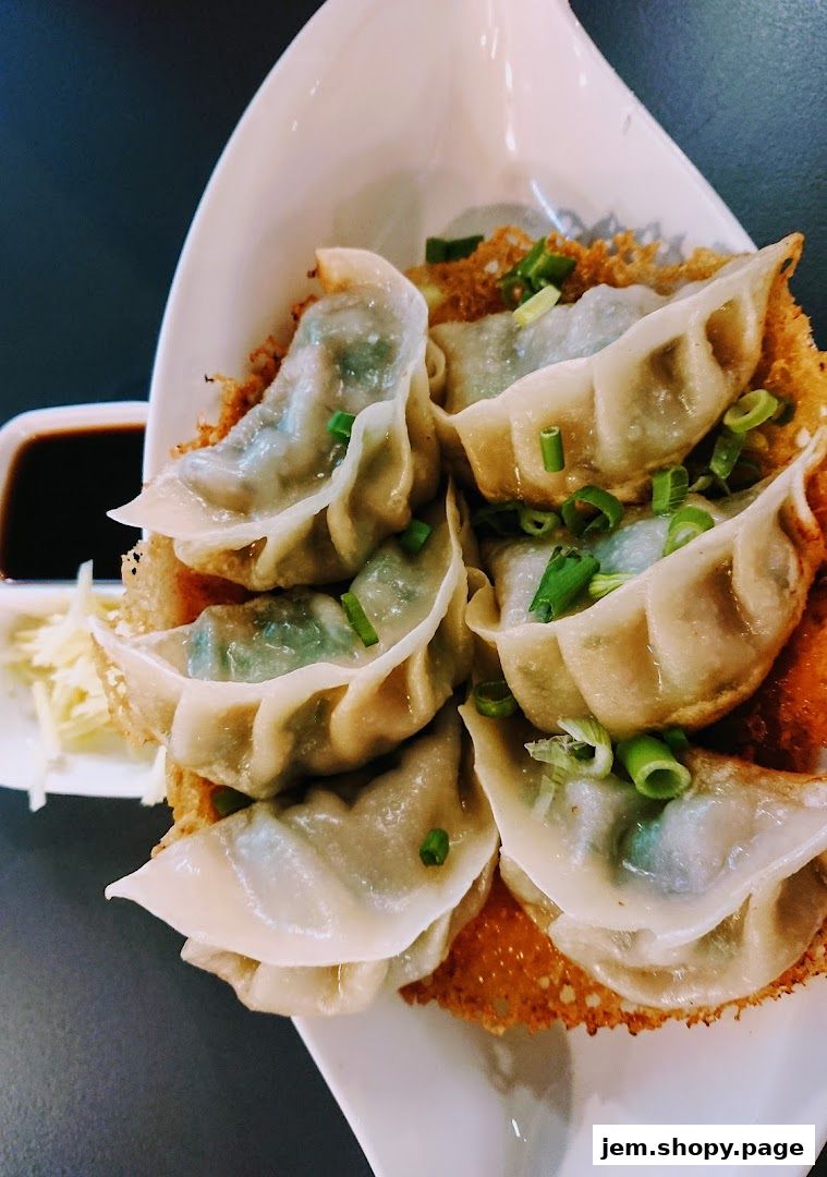 A plate of pan-fried dumplings garnished with chopped green onions and a side of dipping sauce.
