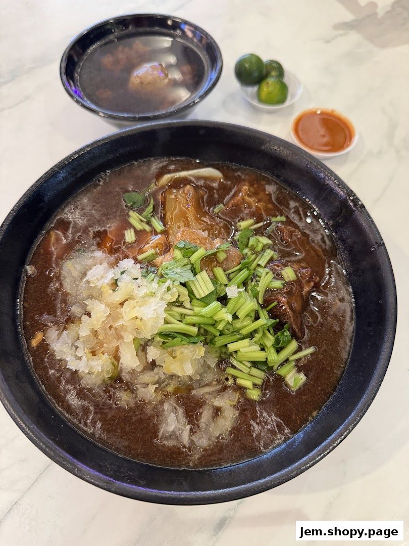 A steaming bowl of beef noodles with broth, meat, and fresh toppings.