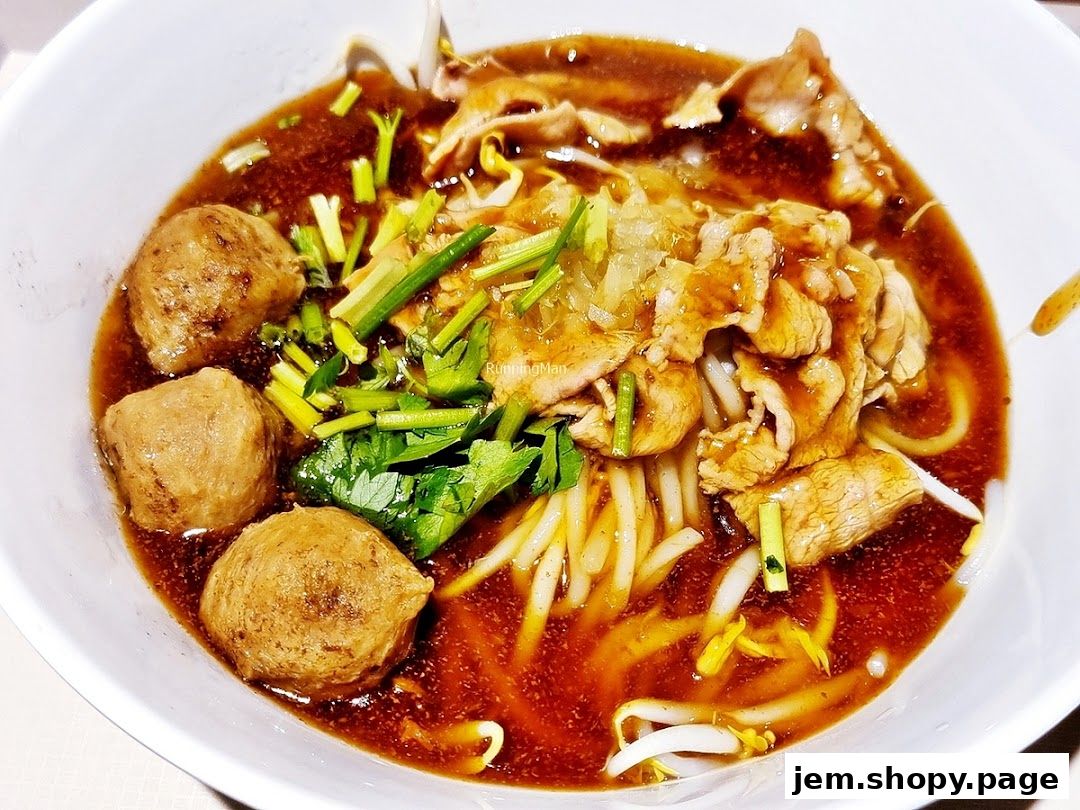 A close-up shot of a delicious bowl of beef noodles with meatballs and fresh herbs.