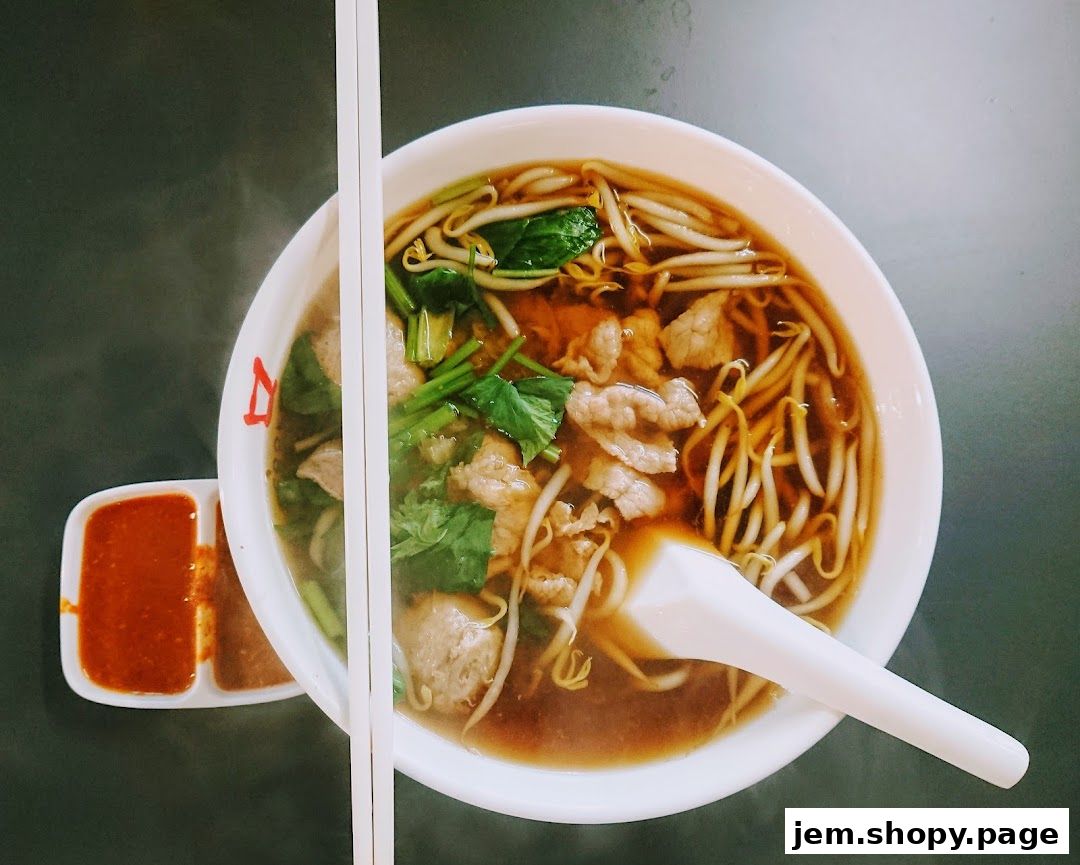 A steaming bowl of beef noodles with chopsticks and dipping sauces.