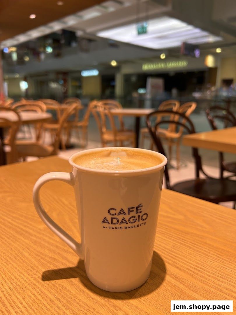 A close-up of a coffee mug with 'Café Adagio by Paris Baguette' logo on a wooden table.