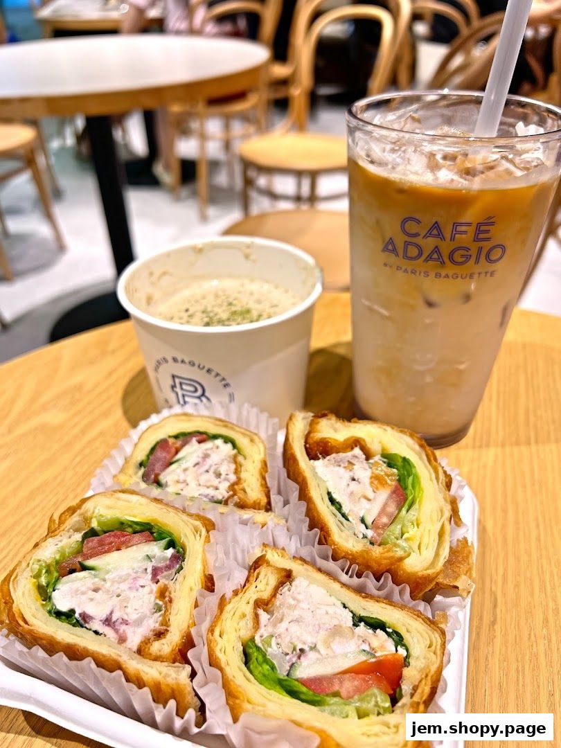A close-up of a meal from Paris Baguette, featuring sandwiches, soup, and iced coffee.