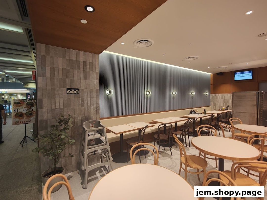 Interior of a modern cafe with tables, chairs, and a menu board.