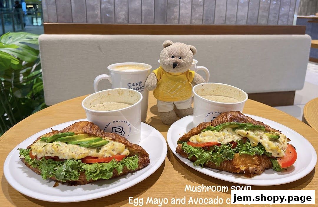 Two croissant sandwiches with egg mayo, avocado, lettuce, and tomato, served with mushroom soup and coffee.