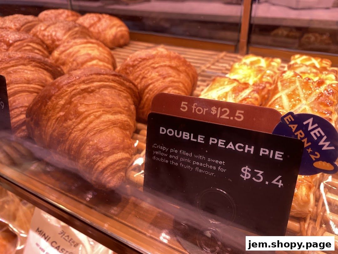 A display of freshly baked croissants and double peach pies with pricing information.