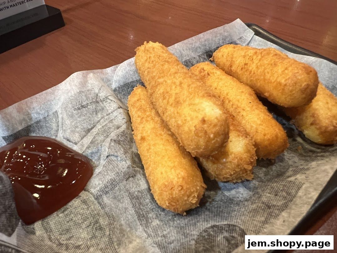Golden-brown fried mozzarella sticks served with a side of ketchup on a black tray.