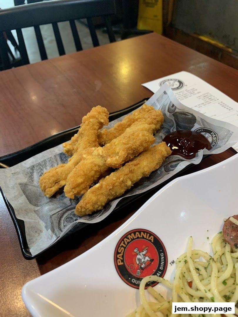 Crispy chicken tenders served with a side of dipping sauce on a table.