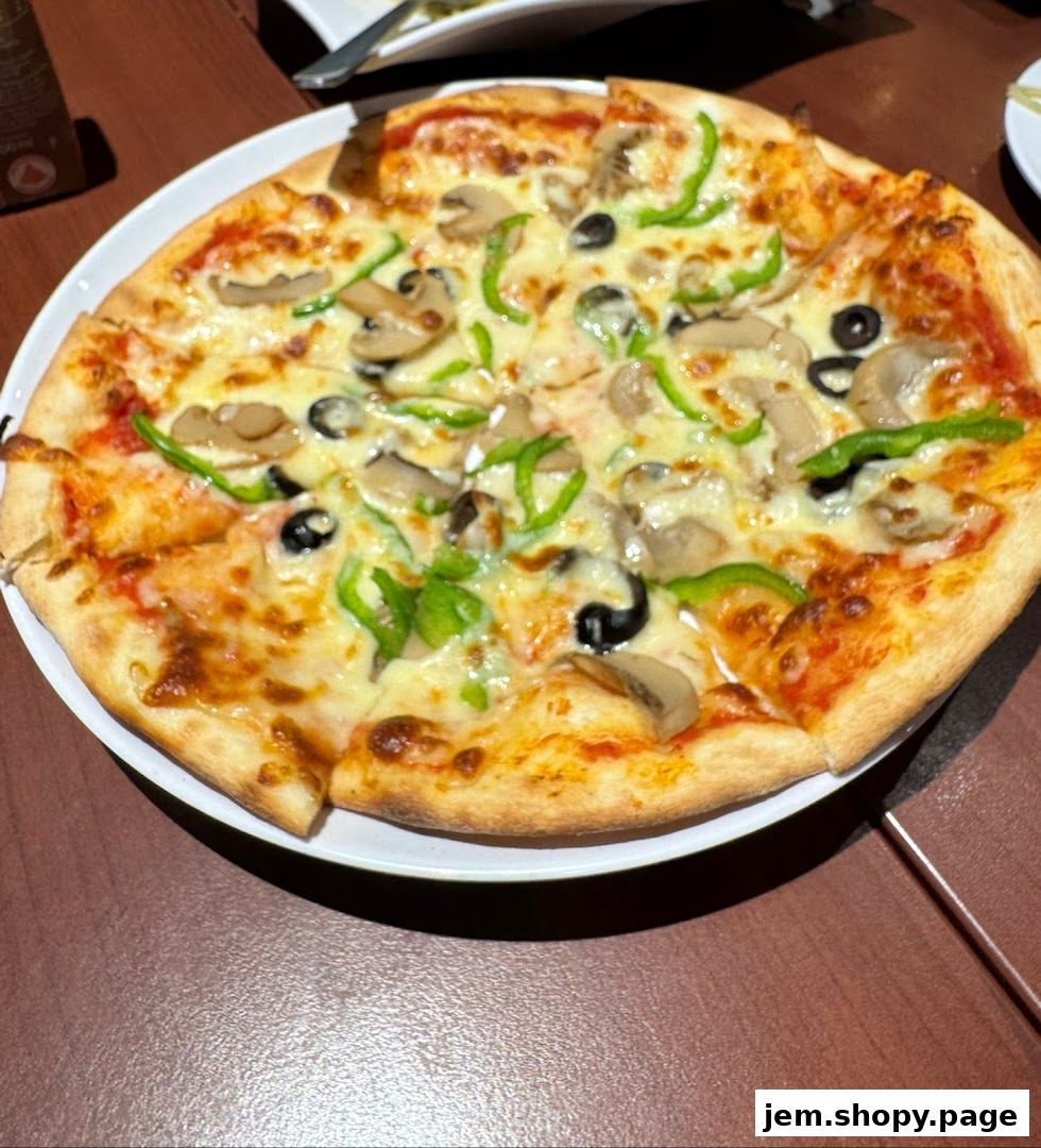 A delicious pizza with mushrooms, olives, and green peppers on a white plate.