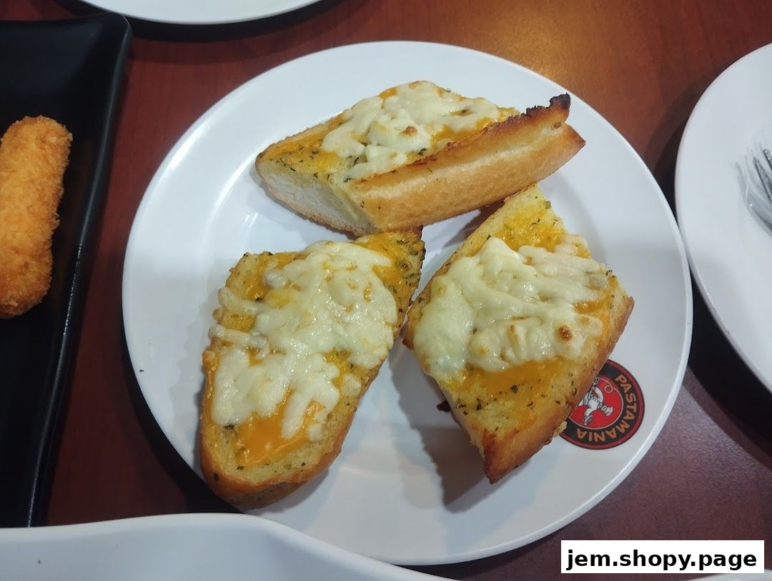 Three slices of cheesy garlic bread served on a white plate with a PastaMania logo.