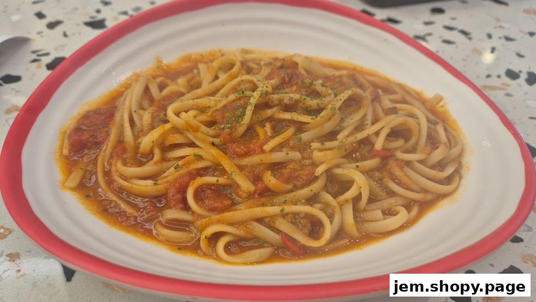 A plate of linguine pasta with a rich tomato sauce and herbs.