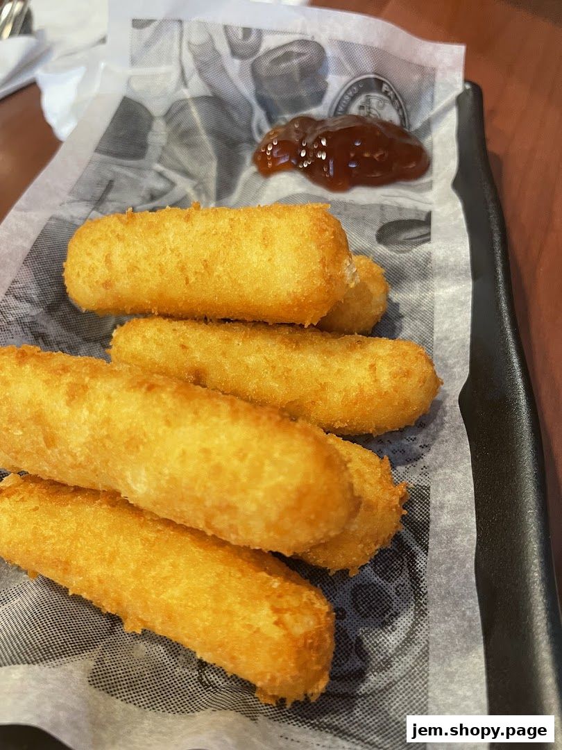Golden-brown fried mozzarella sticks served with a side of dipping sauce.
