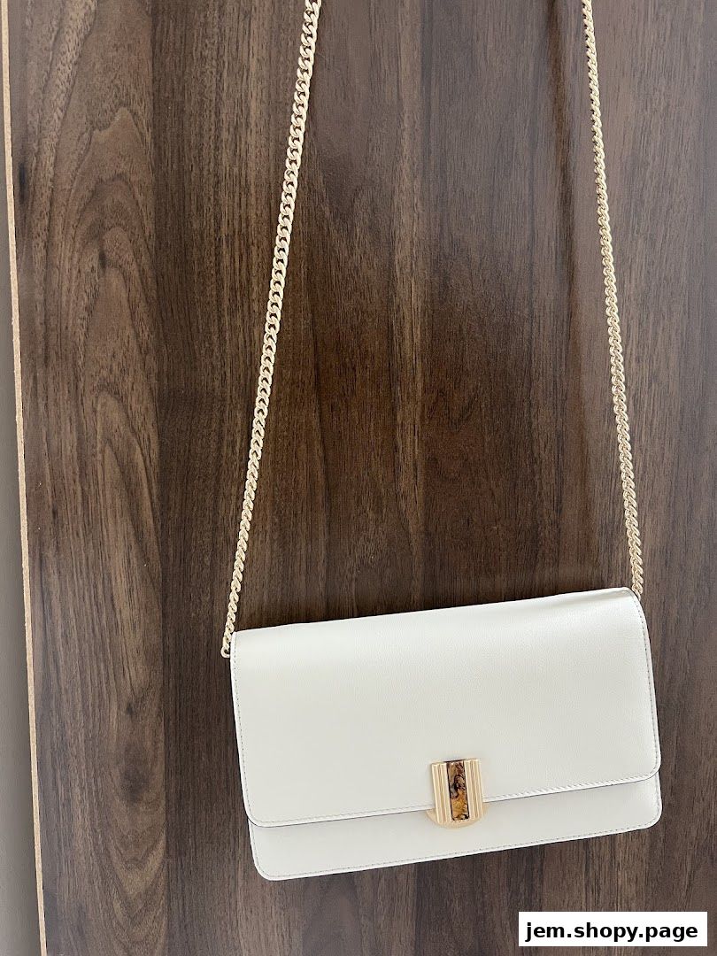 A sleek white clutch bag with a gold chain strap and decorative clasp.