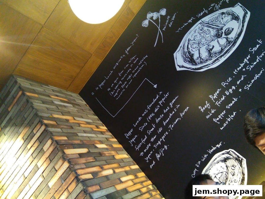 A chalk-drawn menu and information about Pepper Lunch on a black wall.