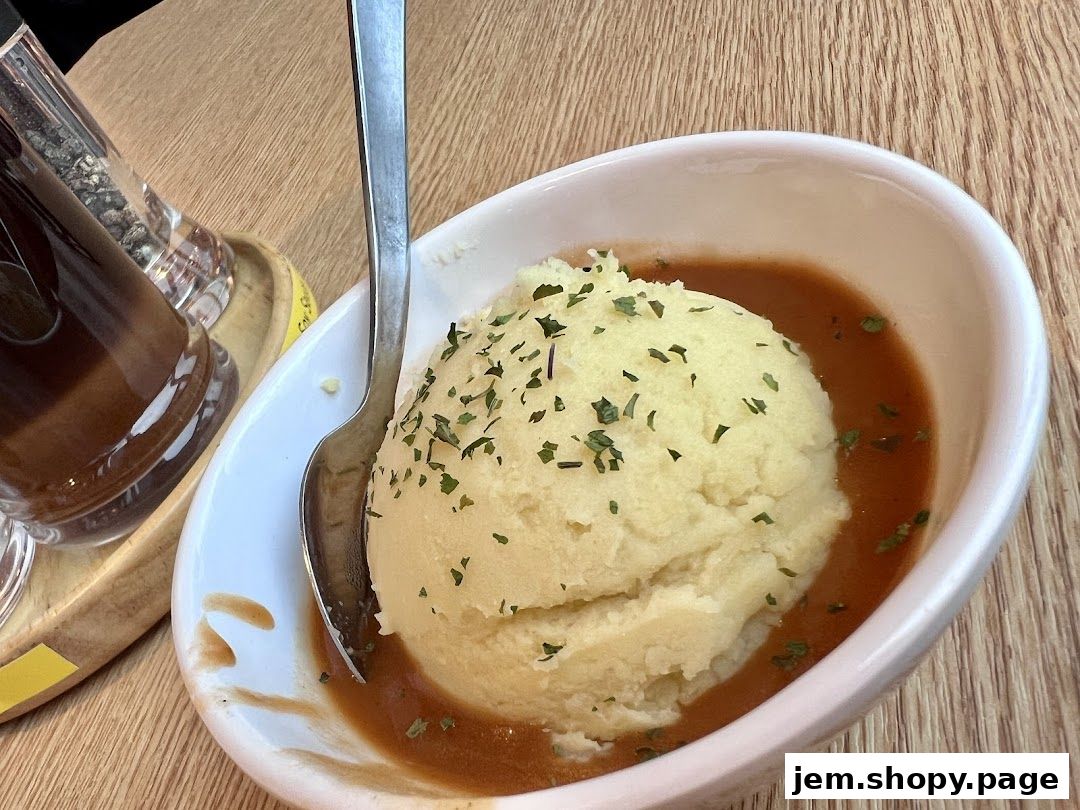A close-up of mashed potatoes with gravy and a spoon in a white bowl.
