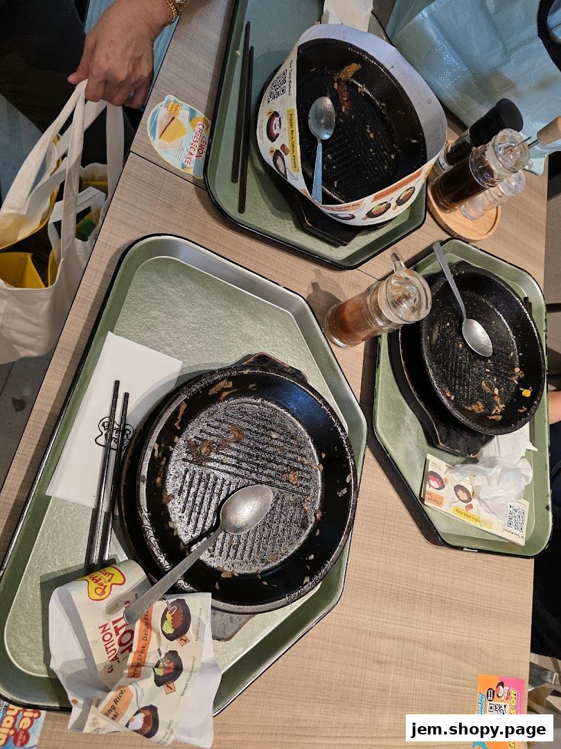 Dirty sizzling plates and condiments on a table after a meal at Pepper Lunch.