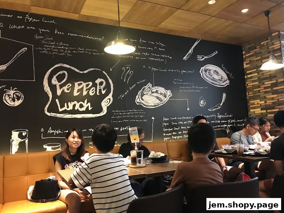 Diners enjoy a meal at Pepper Lunch, with a large chalk-art wall detailing the restaurant's history and menu.