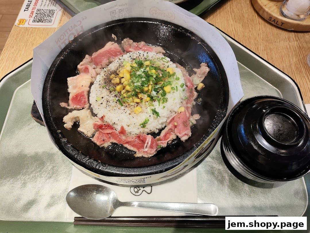 A sizzling hot plate of rice with beef and corn, served with a side of soup.