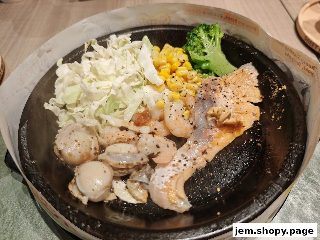 A sizzling hot plate of salmon, shrimp, and scallops with vegetables.
