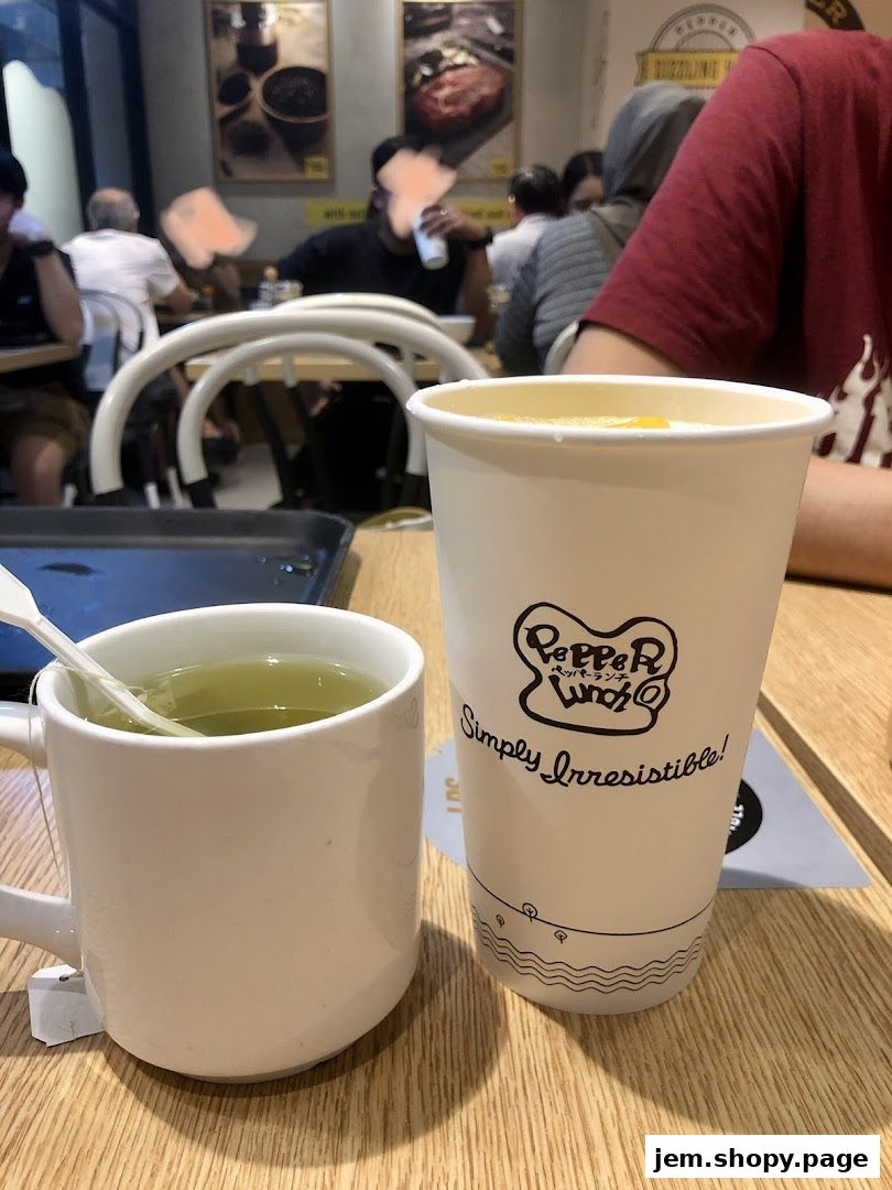A close-up of a cup of tea and a takeaway drink at Pepper Lunch.