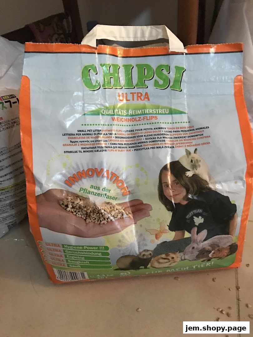 A bag of CHIPSI ULTRA pet litter made from softwood flakes, featuring small animals and a child.
