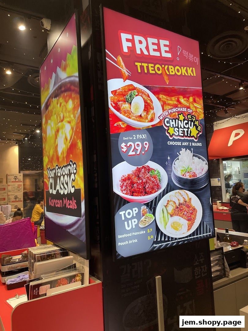 A digital menu board displays Korean street food offers, including Tteokbokki and set meals.