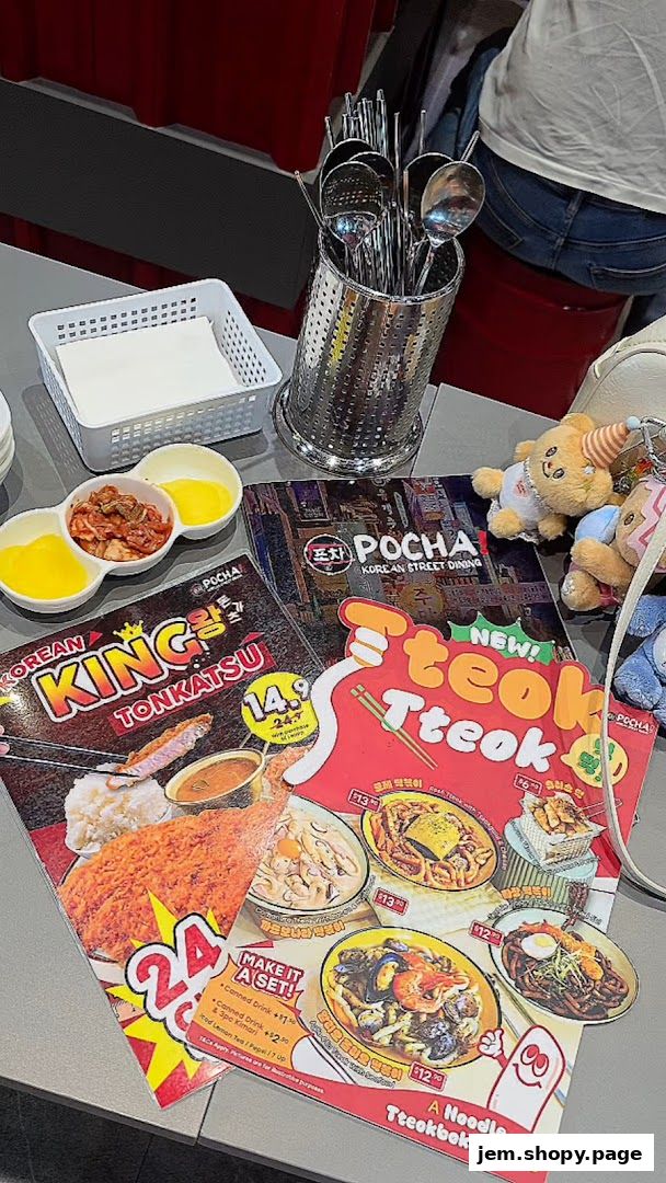 A table at POCHA! Korean Street Dining with menus, kimchi, and utensils.