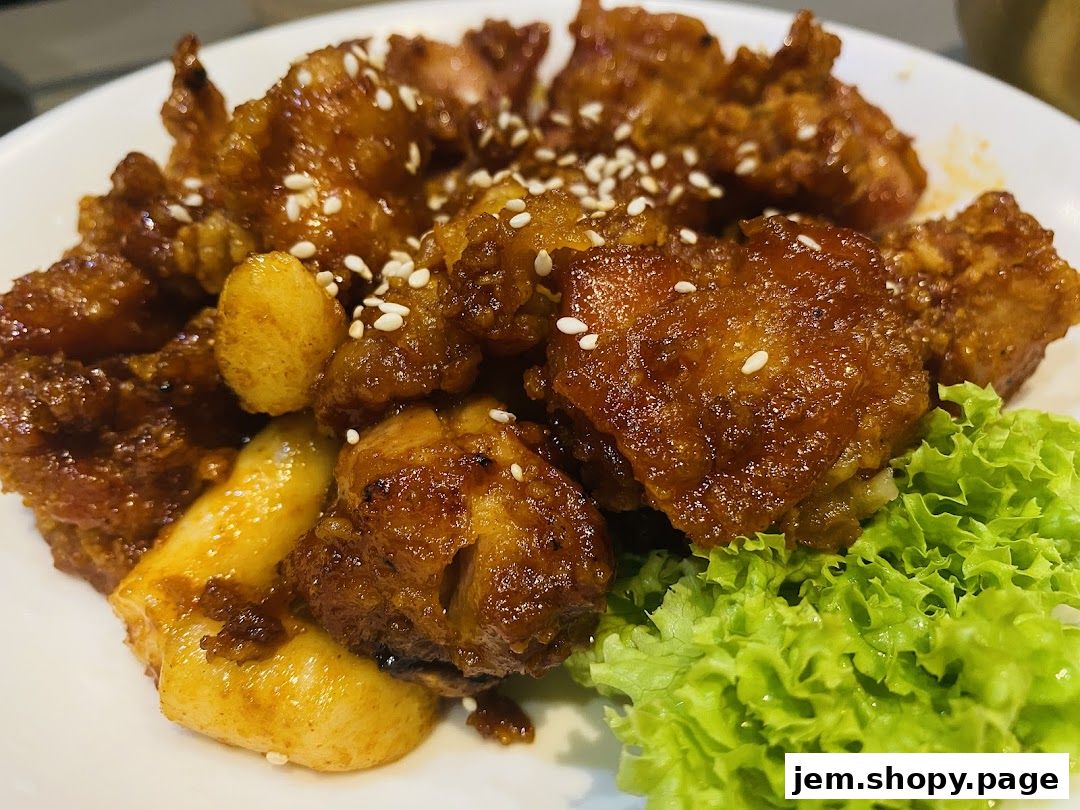 A close-up of Korean fried chicken with tteokbokki and lettuce garnish.