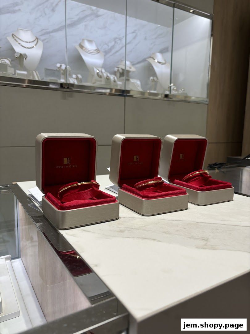 Elegant gold bangles displayed in open red velvet jewelry boxes at Poh Heng Jewellery.