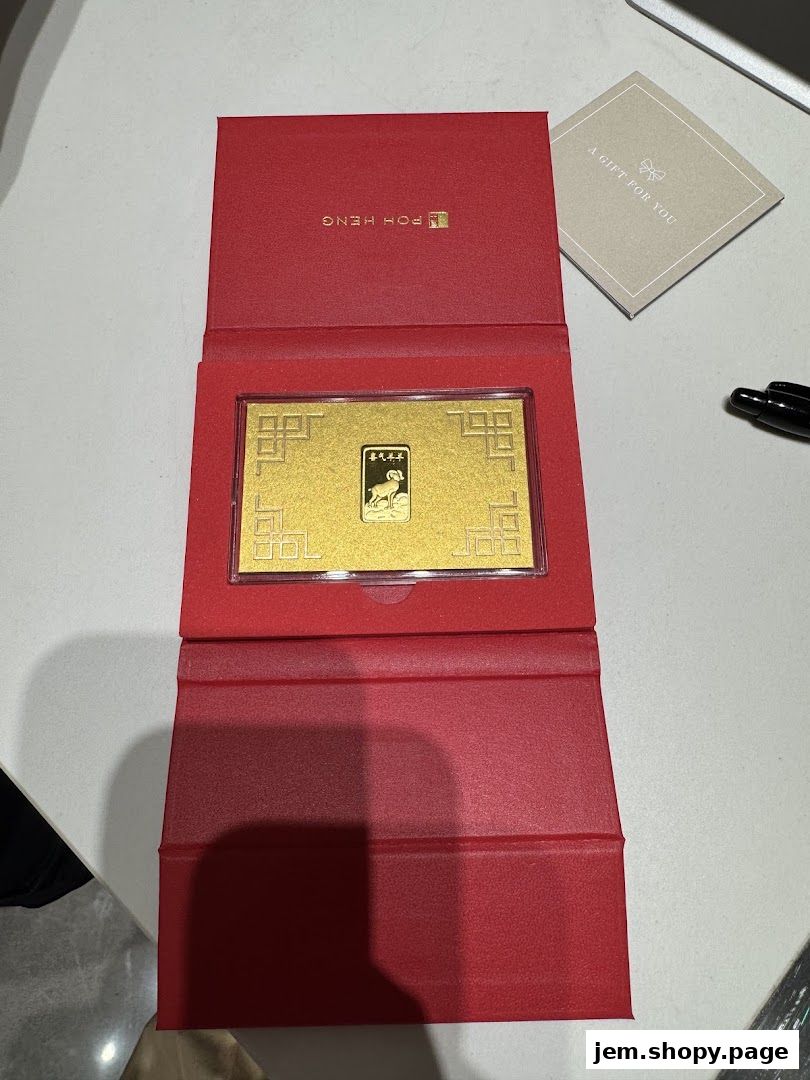 A gold bar with a ram design, presented in a red Poh Heng Jewellery gift box.