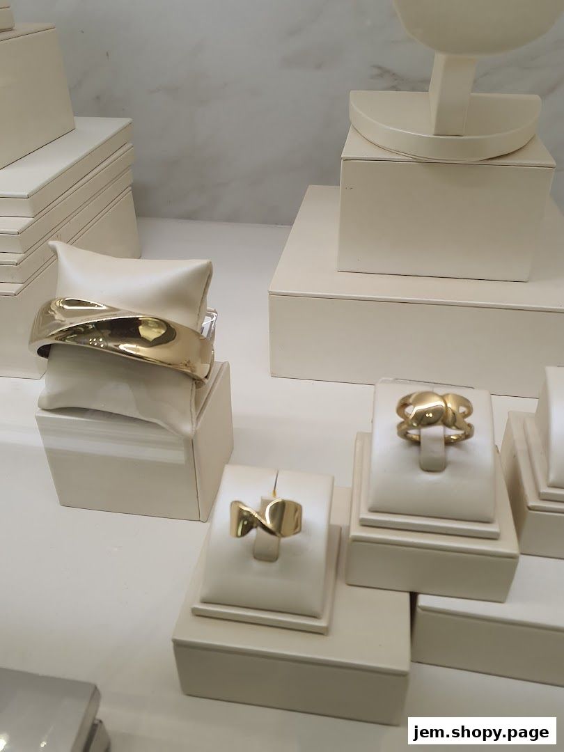 A display of elegant gold jewelry, including a wide bracelet and several rings.