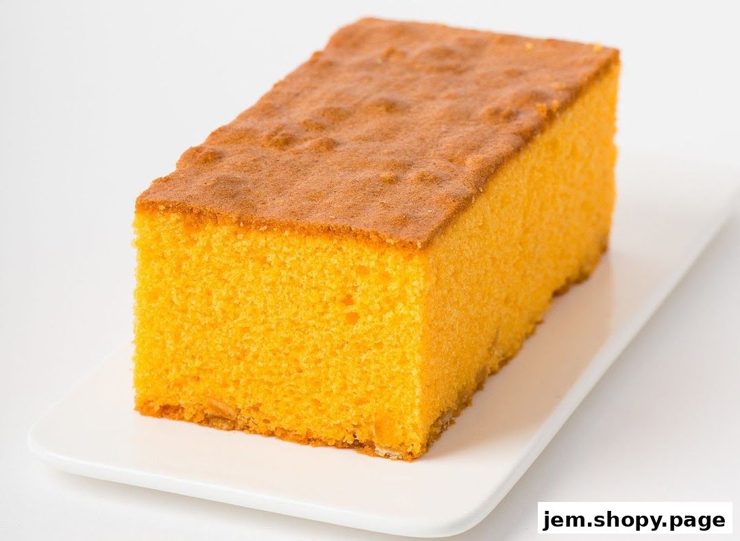 A slice of fluffy, golden-orange cake on a white rectangular plate.