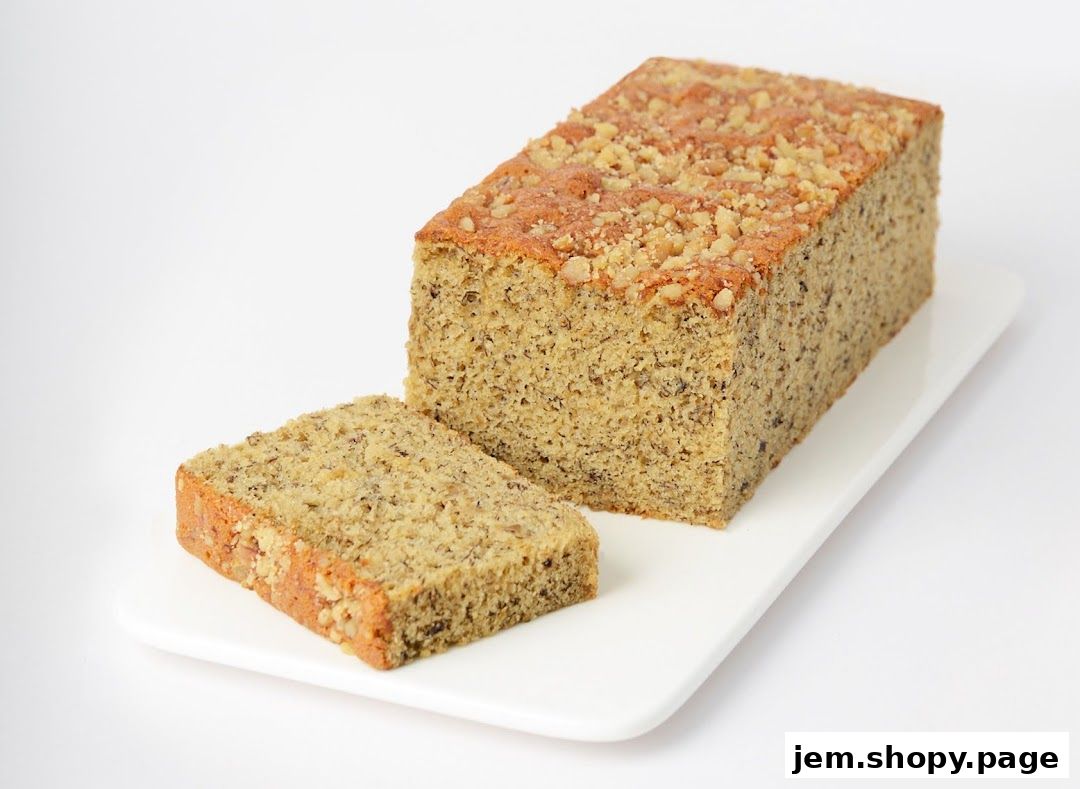 A sliced loaf of banana nut bread topped with chopped nuts on a white platter.