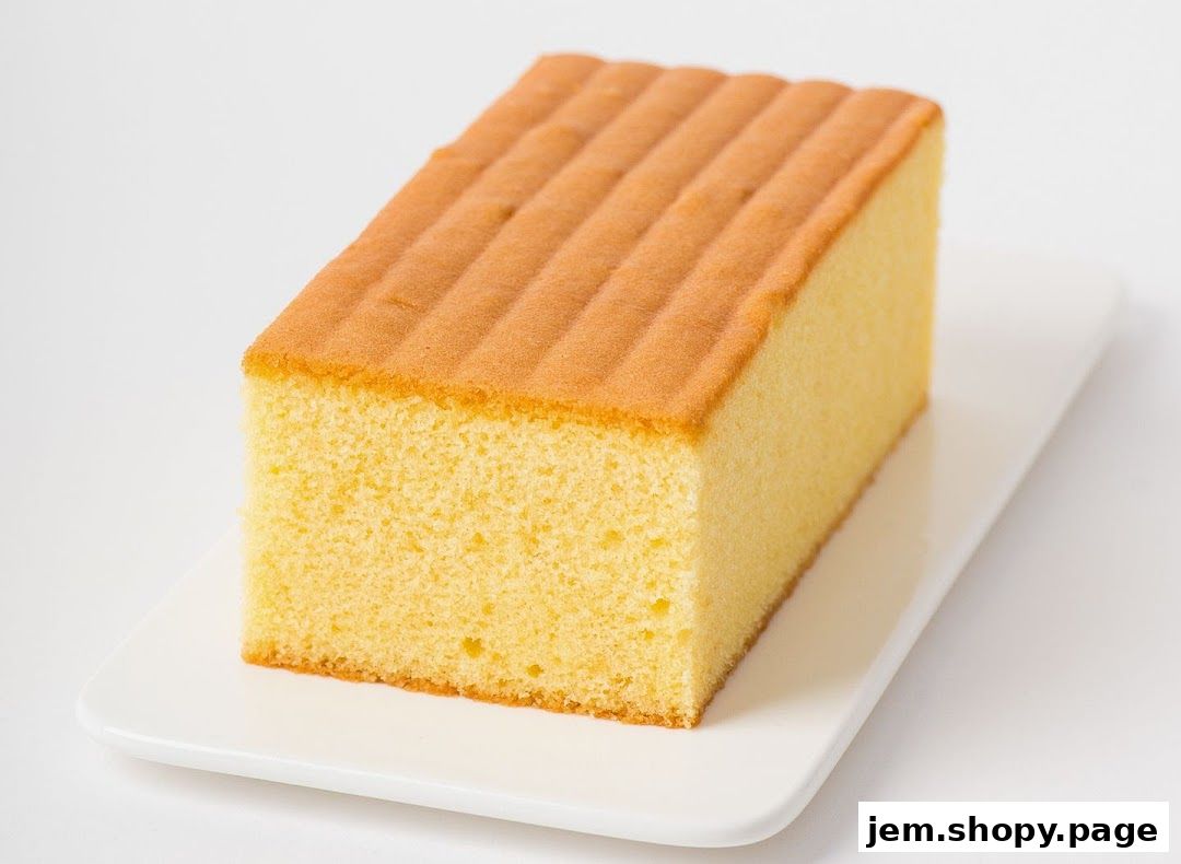 A slice of fluffy, golden sponge cake on a white rectangular plate.