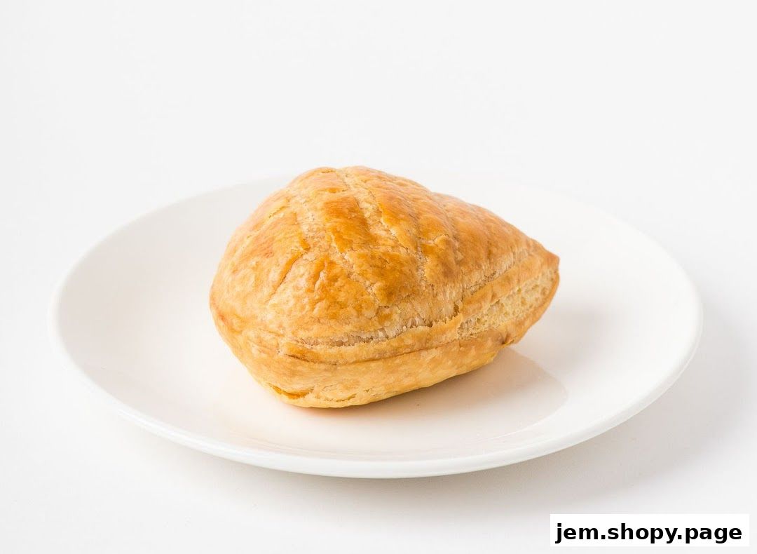 A golden-brown puff pastry on a white plate against a white background.