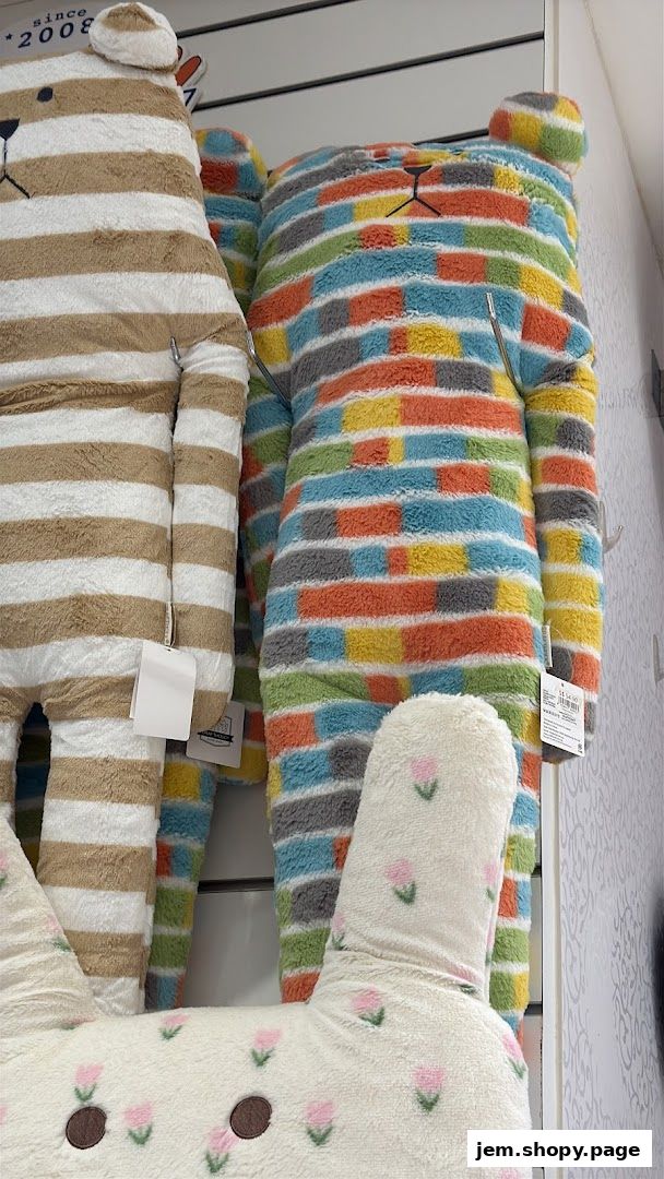 Plush teddy bear-shaped pillows with colorful stripes and floral patterns.