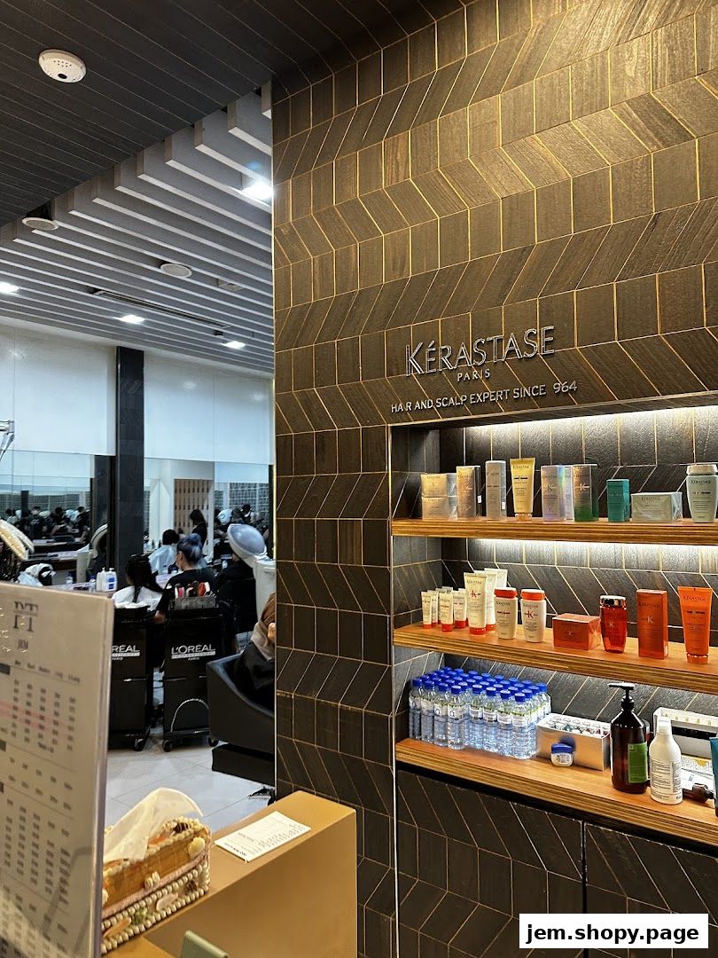 Interior of a hair salon with shelves of Kérastase products and clients receiving services.