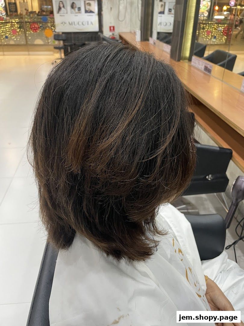 A person's layered brown hair with subtle highlights in a salon setting.