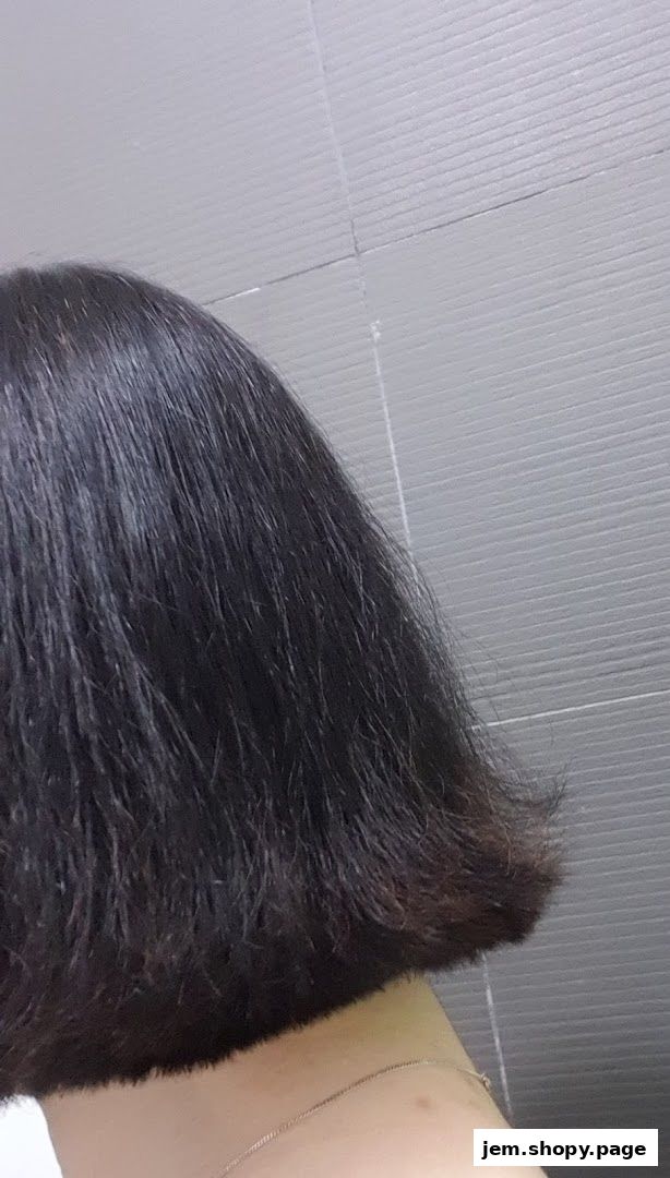 A close-up shot of a person's dark, bob-cut hair against a grey tiled background.