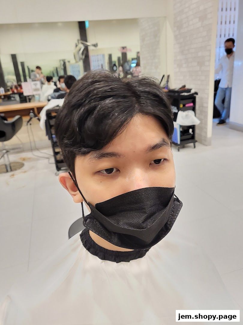 A person wearing a mask and cape in a hair salon, with stylists and clients in the background.